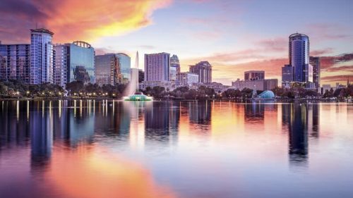 Vibrant sunset skyline view of downtown Orlando, Florida, reflecting on the calm waters of Lake Eola