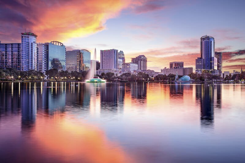 Vibrant sunset skyline view of downtown Orlando, Florida, reflecting on the calm waters of Lake Eola